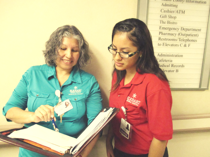 Elkhart General Hospital (EGH) employee showing younger EGH employee contents of binder